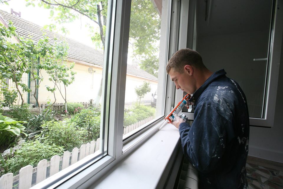 Man running a bead of caulk along the frame of a new window