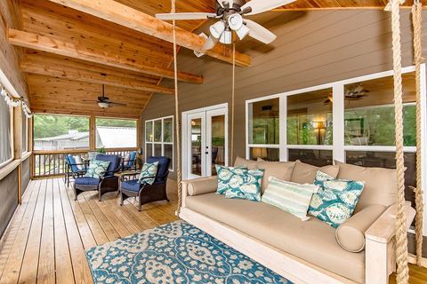 Screened porch with a hanging daybed, patterned cushions, ceiling fans and a plank floor